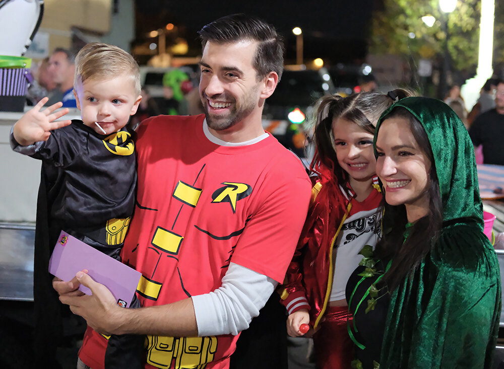 A family of Super Heroes are all smiles.